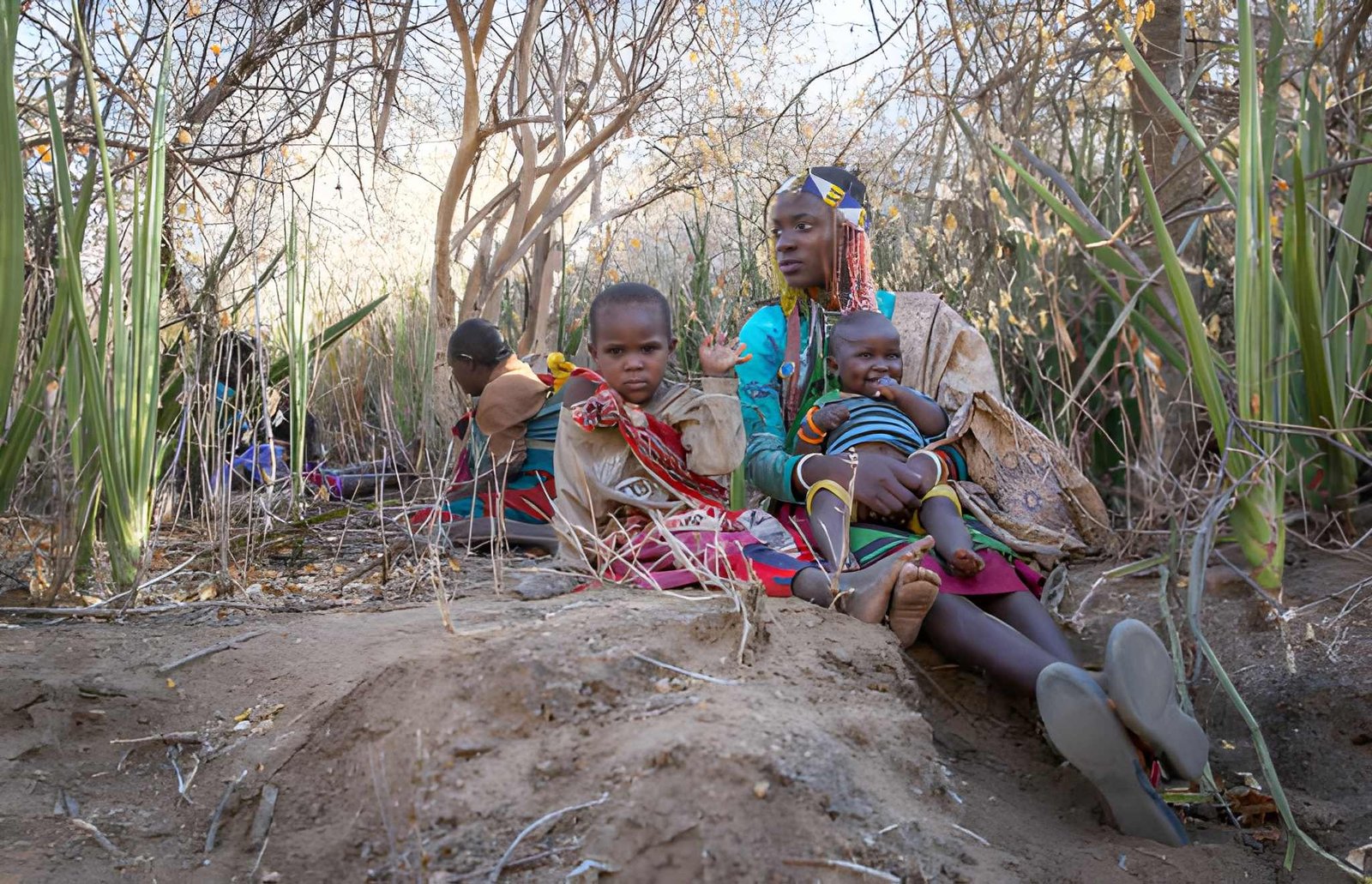 Hadzabe family/community members sitting together outside under a shelter.