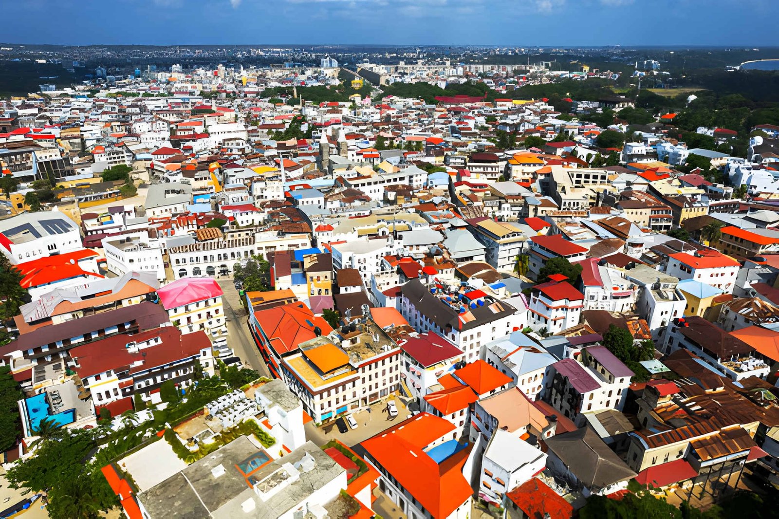 High-angle panoramic view of dense red-tiled roof buildings and streets in a coastal historic city.