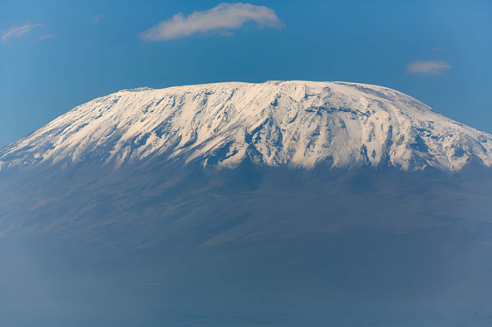A clear view of Mount Kilimanjaro's snow-capped, glacier-covered peak under a crisp blue sky.