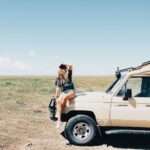 woman in black shirt and blue denim jeans standing on brown dirt road during daytime