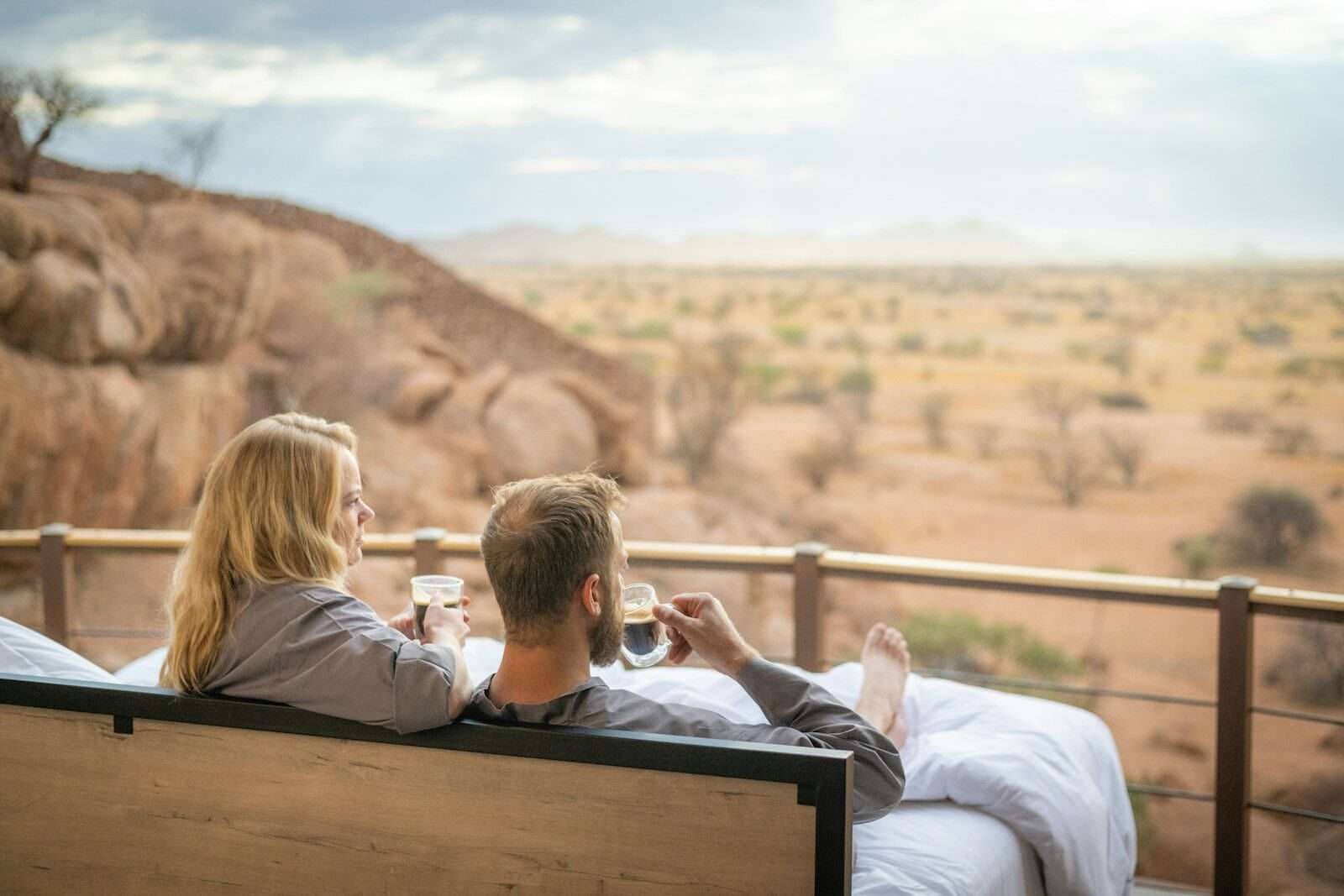 a man and a woman sitting on a bench with a glass of wine