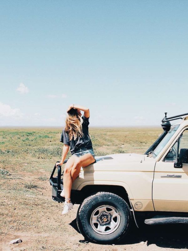 woman in black shirt and blue denim jeans standing on brown dirt road during daytime